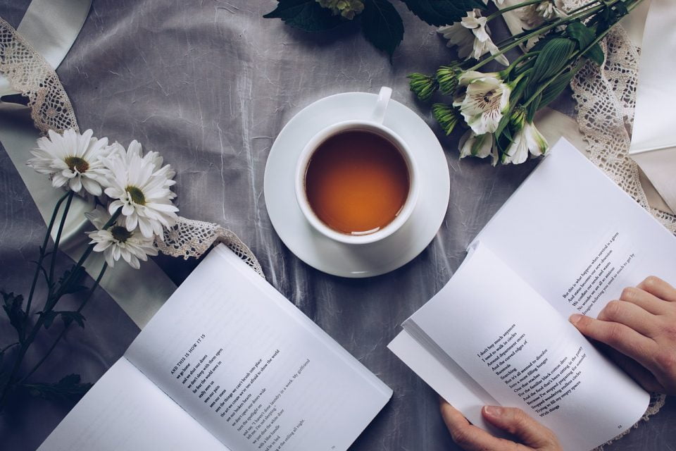 Libros de poesía, una taza de té y flores sobre una mesa